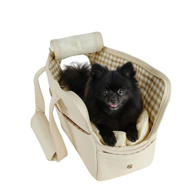 Small black dog sitting in a beige pet carrier with a checkered pattern on a white background