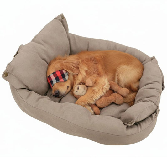 Dog sleeping in a beige pet bed with a plaid eye mask and plush toy.