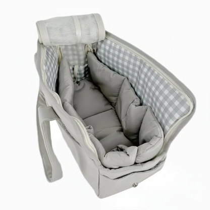 Gray baby crib with checkered sides and soft bedding on a white background