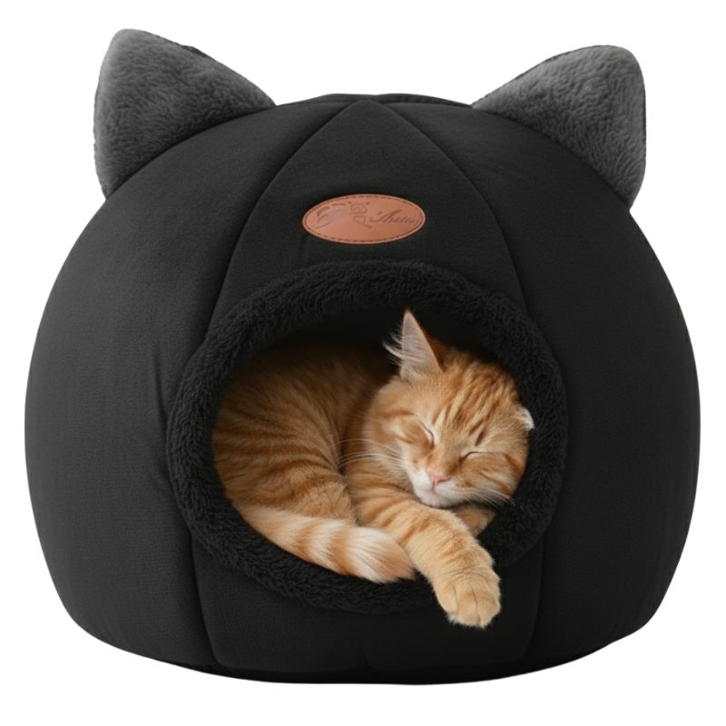 Black pet bed with cat ears containing a sleeping orange tabby cat on a white background
