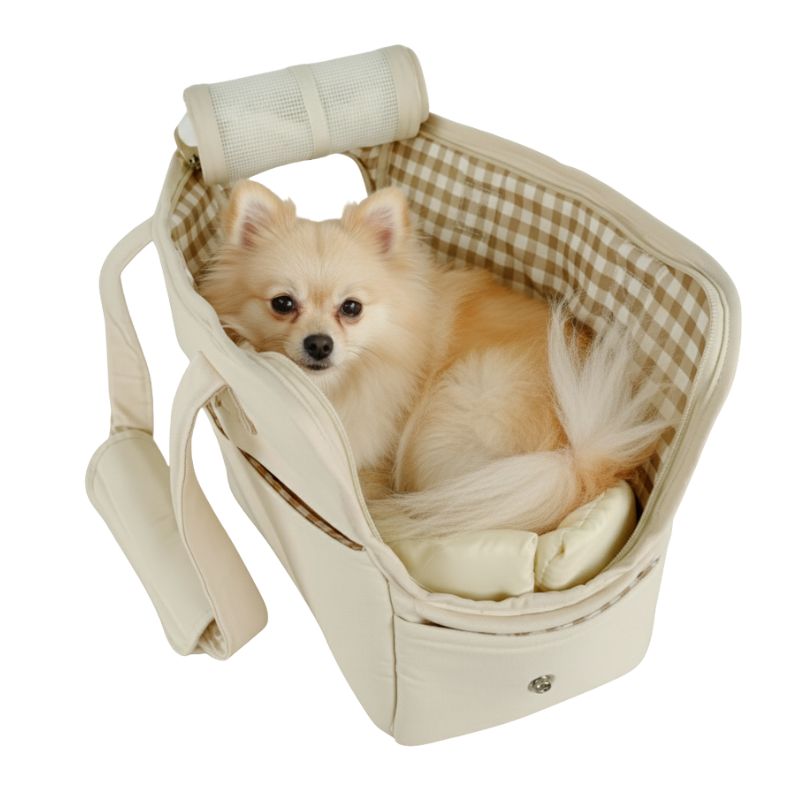 Small dog sitting in a beige pet carrier with a checkered interior on a white background