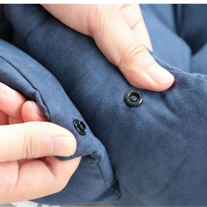 Close-up of a person buttoning a blue garment with black buttons.